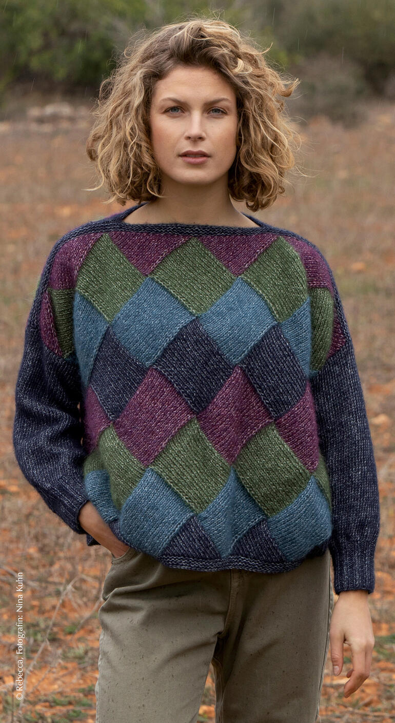 Frau trägt einen bunten Pullover mit Karomuster in einem herbstlichen Wald.