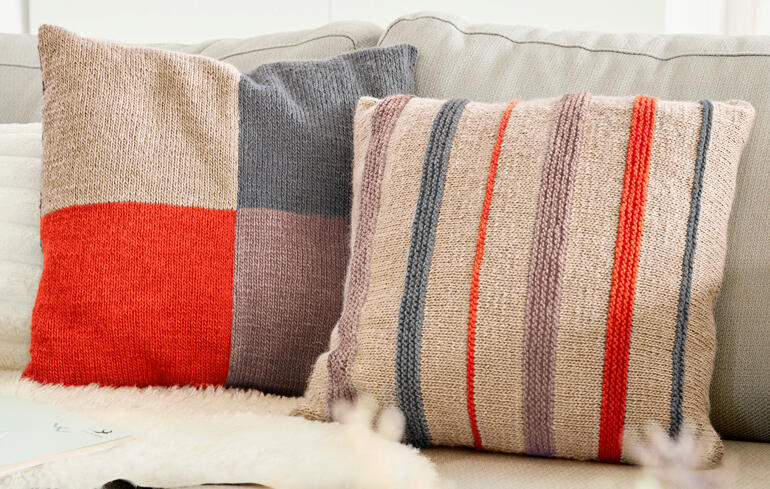 Zwei Kissenhüllen mit geometrischen Mustern auf einem hellen Sofa.