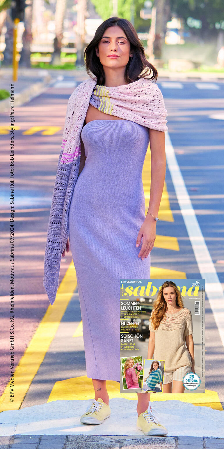 Frau in lila Kleid trägt eine Stola aus Brillianto, posierend auf einer Straße im Freien.