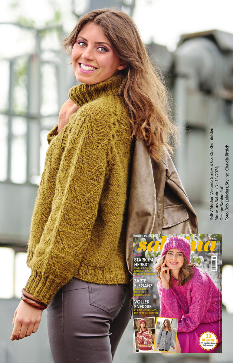 Frau trägt einen olivgrünen Pullover aus Fenella, steht vor einem urbanen Hintergrund.