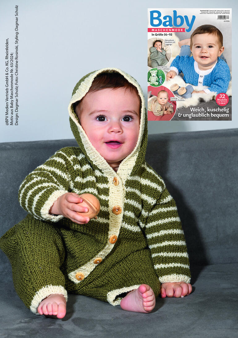 Baby in einem gestreiften Overall mit Fäustlingen aus Onda, schaut in die Kamera.