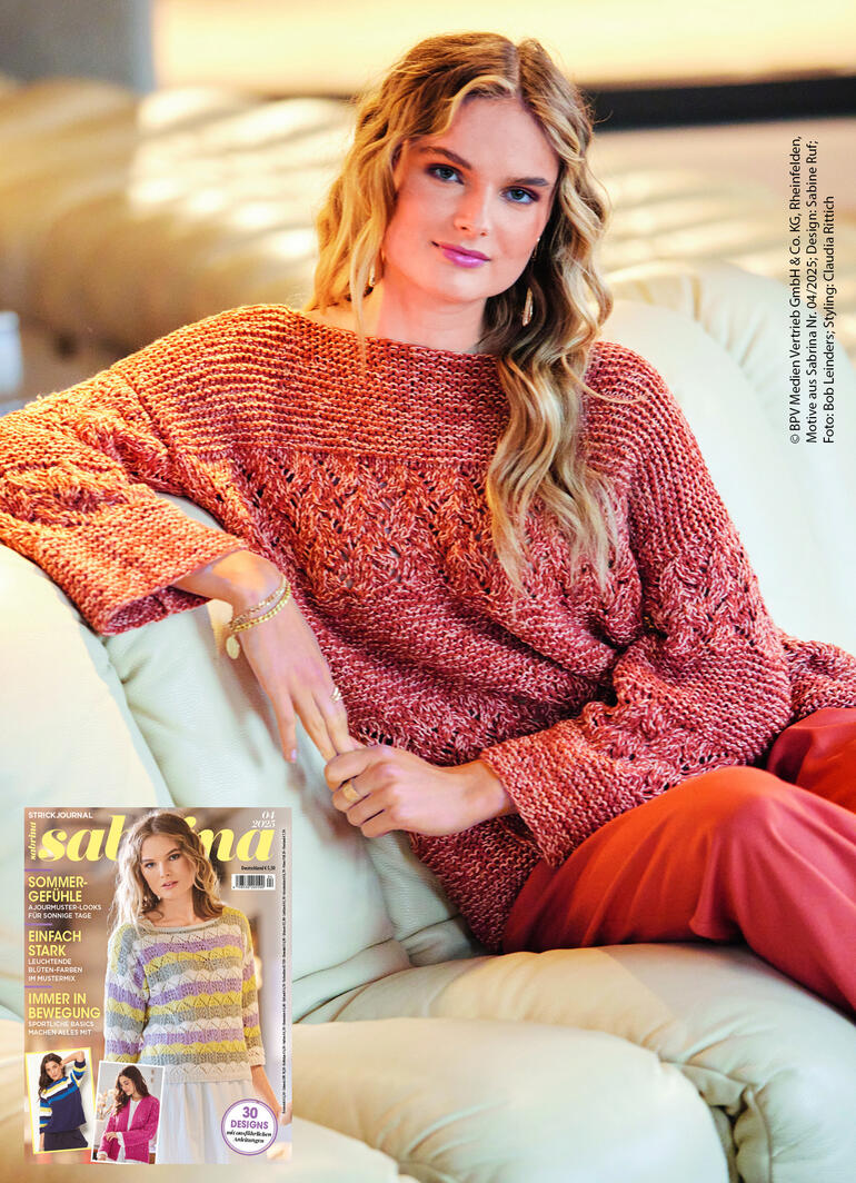 Frau in rotem Pullover mit Struktur sitzt auf einer Couch, entspannt und lächelt.