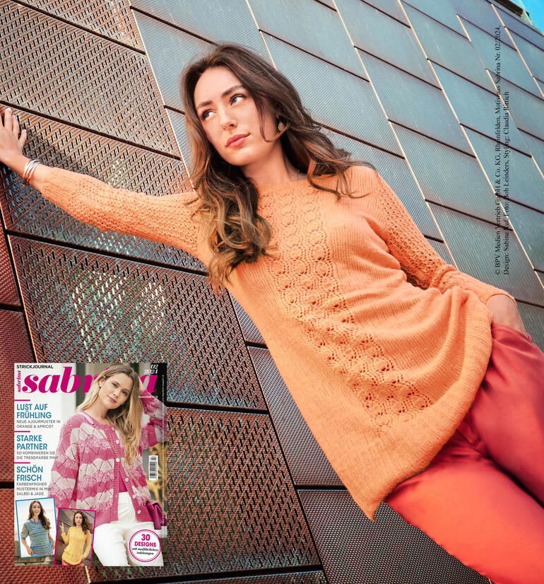 Frau in tailliertem Longpulli aus Charme steht vor einem modernen Gebäude.