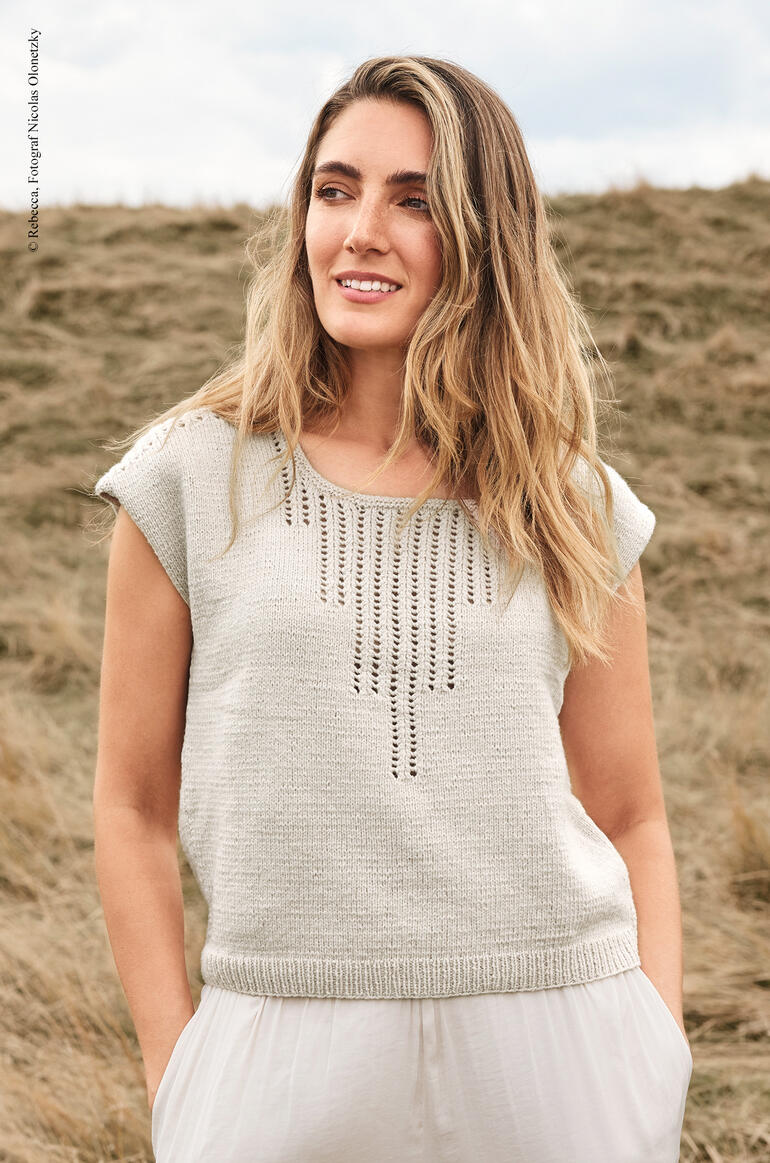 Frau in grauem Top aus Elida steht auf offenem Feld.