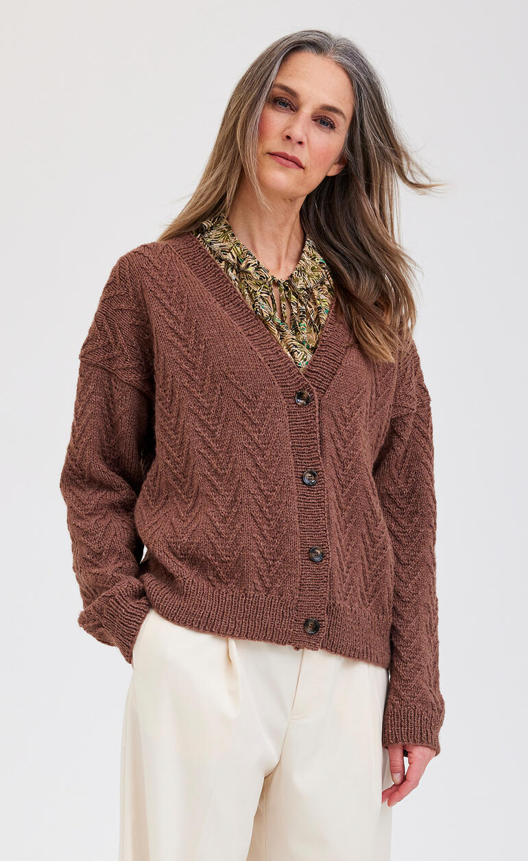 Braune Jacke aus Aparta-Nova mit strukturiertem Muster, getragen von einer Frau.