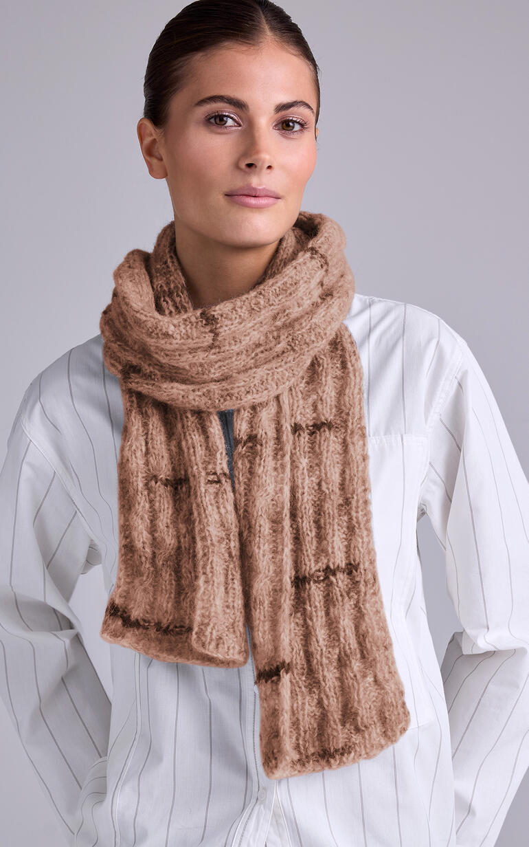 Beiger Schal aus Stoccolma, getragen von einer Frau mit schickem Look.