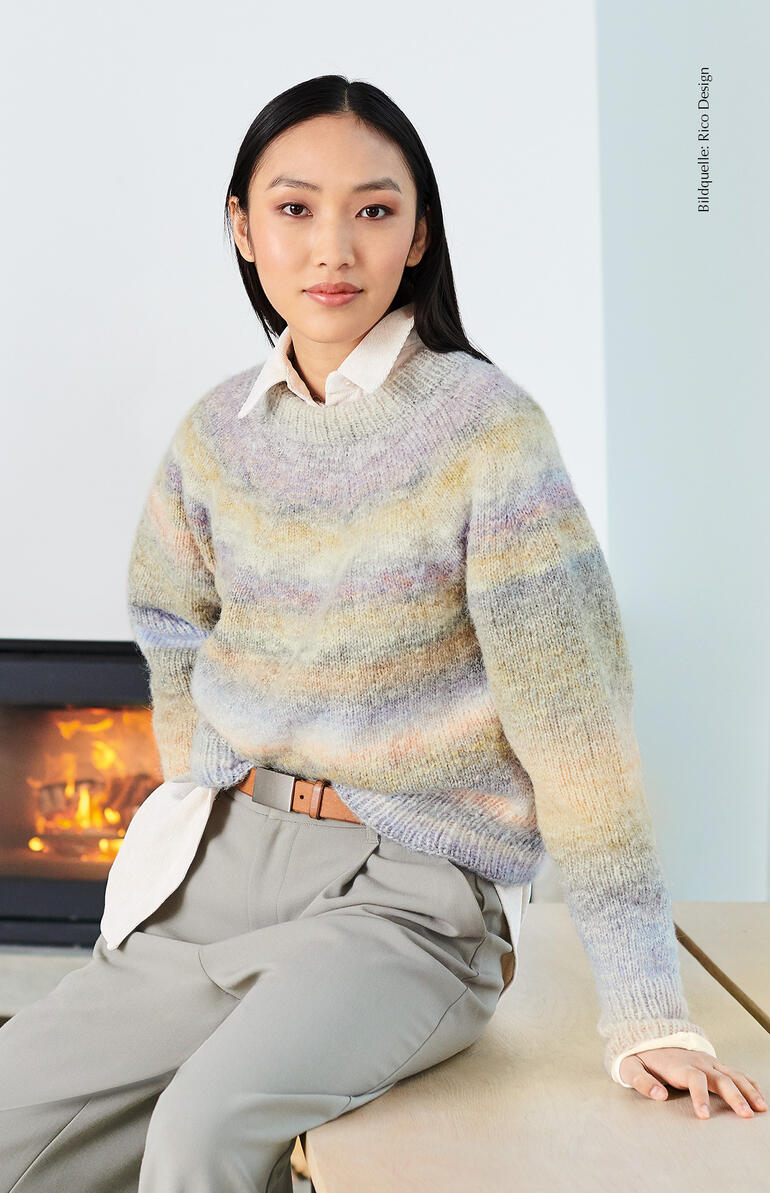Pullover aus Creative Painted Power in zarten Pastelltönen, sitzt auf einem Tisch.
