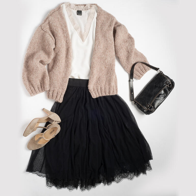 Beige Jacke über einem weißen V-Ausschnitt-Shirt, kombiniert mit schwarzem Rock und Schuhen.