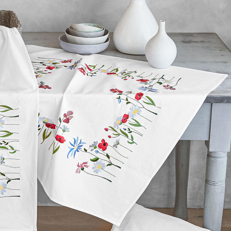 Stick-Ensemble mit romantischen Feldblumenmustern auf Tischdecke.