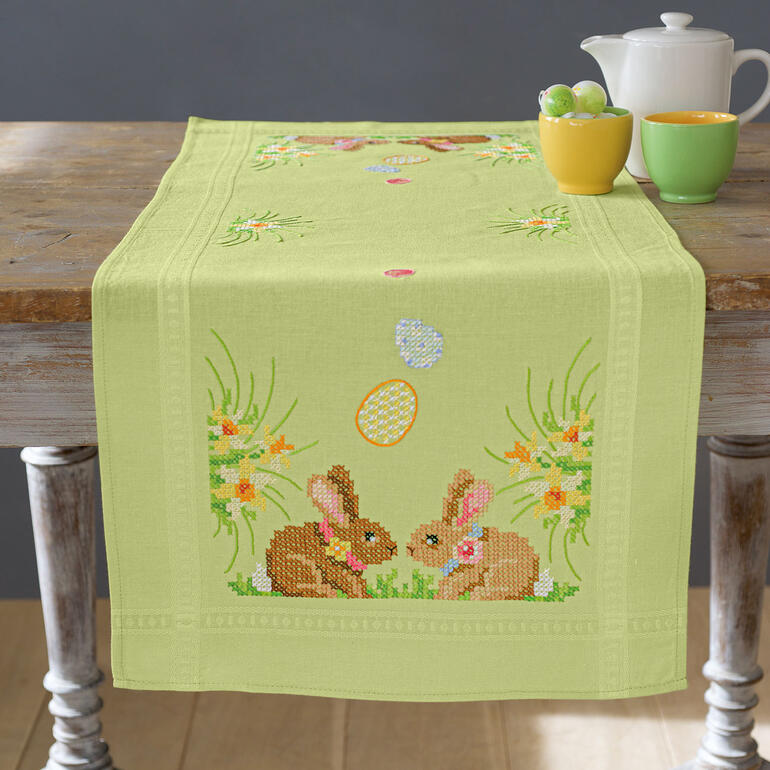 Tischläufer mit Osterhasen und bunten Eiern auf einem fröhlichen Hintergrund.