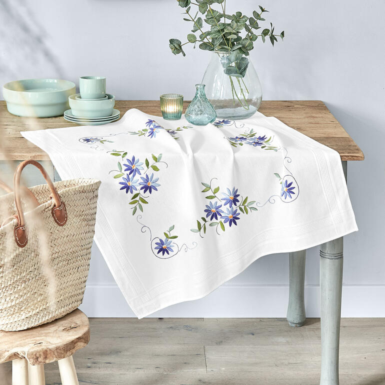 Tischdecke mit blauen Sternen auf einem Tisch mit Blumenvasen.