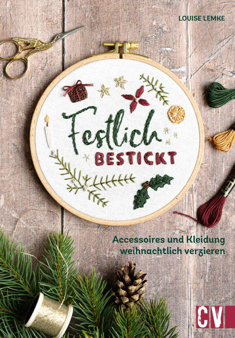 Buch über festliche Stickereien mit weihnachtlichen Motiven auf einem Tisch.