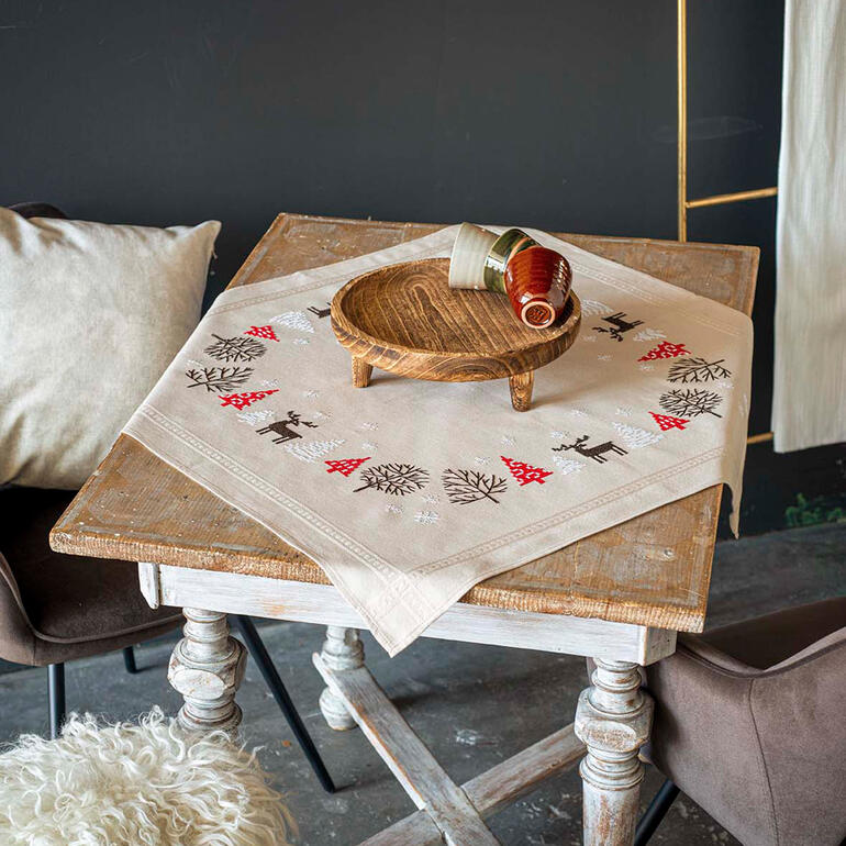 Tischwäsche mit weihnachtlichen Motiven auf einem rustikalen Tisch.