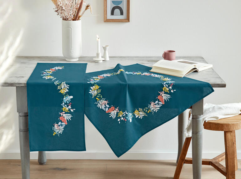 Tischwäsche mit bunten Blumenmotiven und dekortivem Blätterdesign.