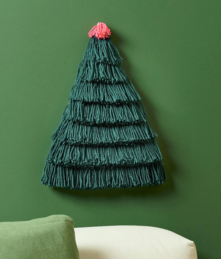 Wandbehang in Form eines Weihnachtsbaumes aus grünem Garn.